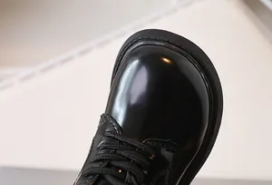 Macro shot of children's black patent leather shoes with round toe and lace-up detail