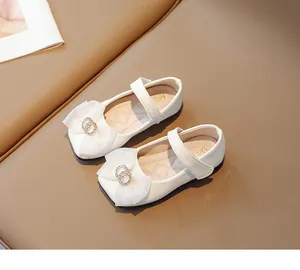 Detailansicht weißer Mädchen-Mary-Janes mit Spitzenschleife und Strass-Schnalle