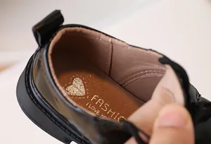 Close-up of kids leather shoe with golden heart logo and polished black finish