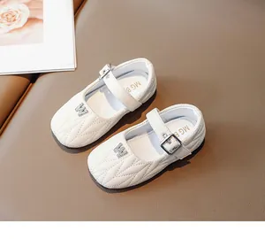 Detail of white girls Mary Jane shoes featuring quilted texture and rhinestone M decoration