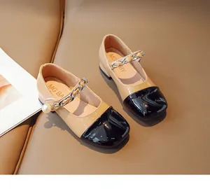 Detail of girls' two-tone Mary Jane shoes with metal chain and pearl decorative strap