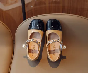 Close-up of children's Mary Jane shoes featuring silver chain and pearl detail