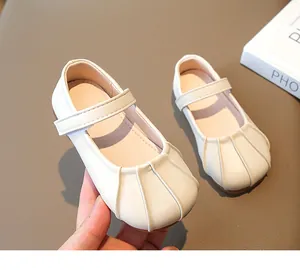 Detalle de merceditas crema para niña con diseño de punta plisada y cierre de velcro