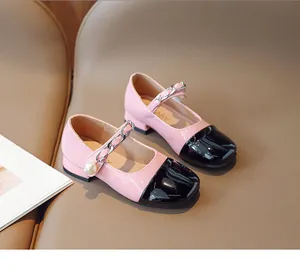 Detail of pink and black patent leather Mary Janes with silver chain and pearl accent