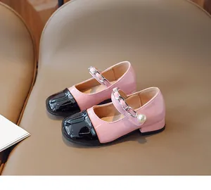 Detail of pink and black patent leather Mary Jane shoes with silver chain and pearl
