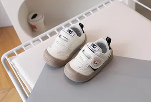 Close-up of baby walking shoes featuring plush bear detail and dual velcro straps