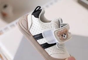 Close-up of baby walking shoes featuring cute bear embroidery and hook and loop strap