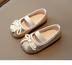 Detail of girls' golden sequin Mary Jane shoes with cream bow and elastic strap