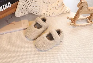 Detail of plush lamb wool Mary Jane baby shoes with Velcro strap on a warm beige rug