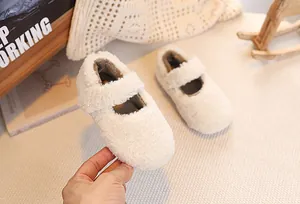 Close-up of white plush Mary Jane baby shoes with fuzzy fleece and adjustable strap