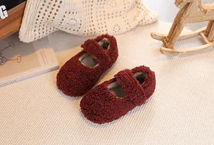 Close-up of burgundy plush Mary Jane shoes for girls with velcro strap on a beige mat