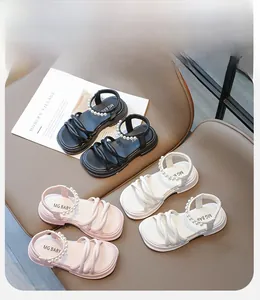 Dettaglio di sandali con perle da bambina in nero, bianco e rosa su superficie in pelle