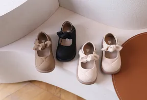 Dettaglio di scarpe Mary Jane da bambina con motivi trapuntati e grandi fiocchi in tre colori