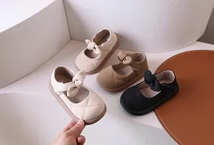 Dettaglio di scarpe Mary Jane trapuntate da bambina in beige, marrone e nero con fiocco