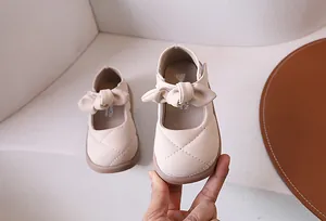 Dettaglio macro di scarpe Mary Jane beige da bambina con punta trapuntata e fiocco