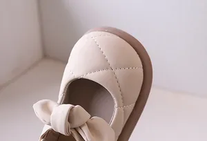 Dettaglio scarpe Mary Jane beige trapuntate da bambina con decorazione a fiocco