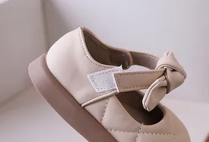 Dettaglio scarpa Mary Jane da bambina con cuciture a rombi, fiocco e cinturino velcro