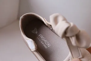 Dettaglio dell'interno della scarpa beige da bambina con logo fashion e cinturino a strappo