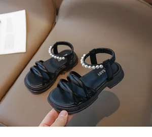 Dettaglio di sandali neri platform con cinturino di perle ed elastico per bambine