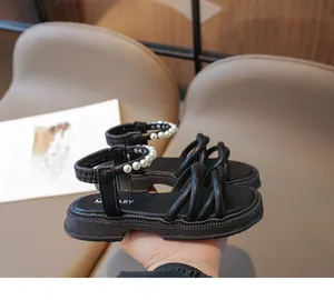 Dettagli di sandali neri per bambini con cinturini incrociati ed eleganti perline