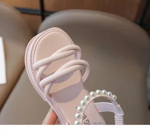Dettaglio di sandali rosa con cinturini incrociati, eleganti perle e suole platform