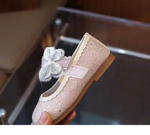 Detailed view of pink glitter Mary Jane shoes with white bow and velcro strap