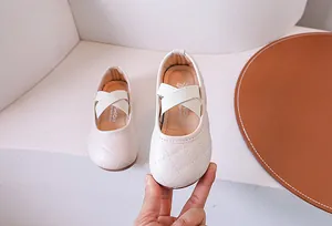 Dettaglio di scarpe da principessa beige per bambina con trapuntatura e cinturini elastici