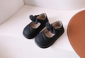 Dettaglio di scarpe Mary Jane nere per bambine con cuciture trapuntate e fiocco grande
