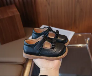 Gros plan sur des Mary Jane noires avec nœud et détails ajourés style brogue