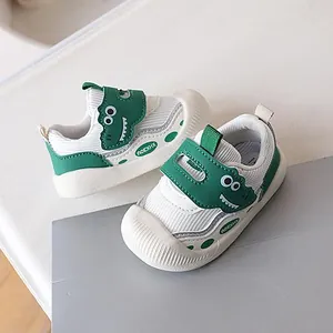 White and green baby toddler walking shoes featuring a cute cartoon dinosaur velcro strap