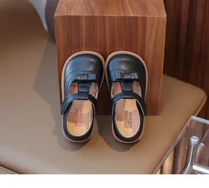Détail de chaussures Mary Jane noires avec nœud et motifs découpés de style richelieu