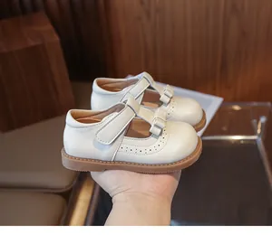 Détail des chaussures Mary Jane blanches avec noeud décoratif et motifs brogue