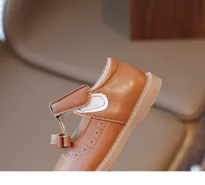 Détail de chaussures de princesse marron pour filles avec nœud et perforations brogue