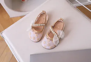 Close-up of girls pink mesh shoes with lace embroidery, pearls, and organza bow detail