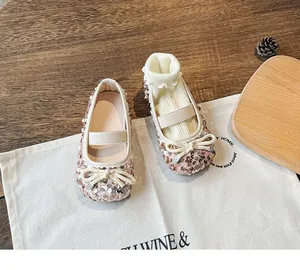 Detailed shot of rose gold sequin Mary Jane baby shoes with bow and ruffled socks
