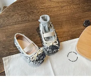 Detail of silver sequin Mary Jane shoes with bow decoration and matching cotton socks