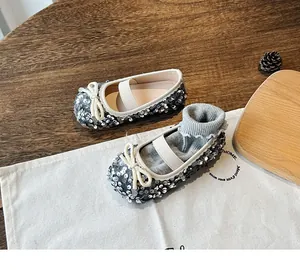 Close-up of silver sequined Mary Jane flats with bow detail and elastic strap