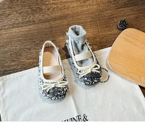 Close-up of silver sequin Mary Jane shoes with bow detail on a rustic wooden tray