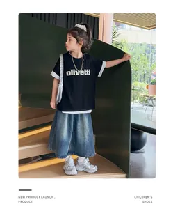 Primo piano di un completo estivo da bambina con t-shirt nera e gonna di jeans blu