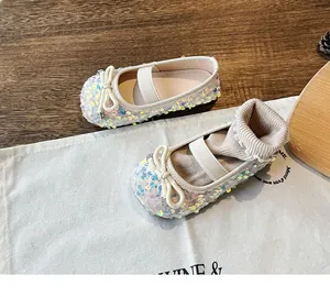 Close-up of girls sequin Mary Jane flats with bow and crystal buckle detail on wood