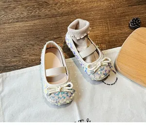 Detailed view of iridescent sequin girl's Mary Jane shoes with bow on a rustic background