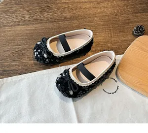 Close-up of black sequined girls Mary Jane shoes with bow decoration and elastic strap