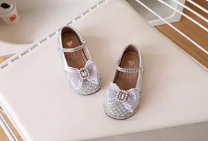Détail d'une chaussure Mary Jane argentée pour enfant avec nœud violet et strass brillants