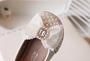 Détail du nœud en résille avec grand strass et perles sur chaussures pailletées enfant