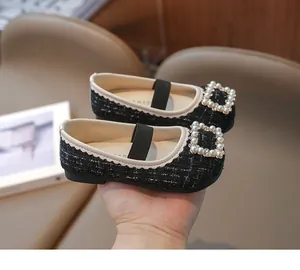 Detalle de los zapatos Mary Jane de tweed negro para niñas con elegante hebilla de perlas