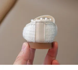 Detalle de los zapatos de princesa de tweed blanco para niñas con perlas e hilo plateado