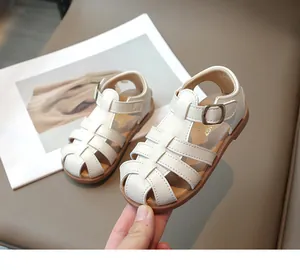 Close-up of white baby sandals with classic woven cage design and non-slip rubber sole