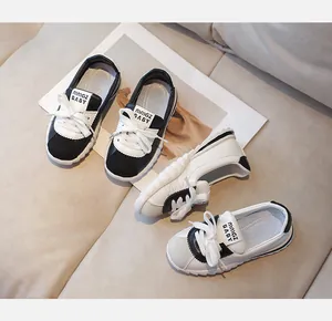 Vue de dessus de baskets enfants noir et blanc avec semelles antidérapantes et lacets blancs