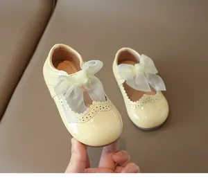 Detail of girls Mary Jane shoes in cream yellow with lace bow and brogue carving