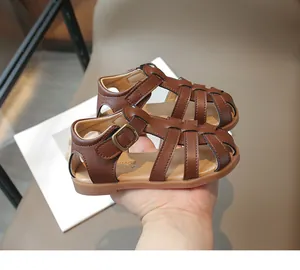 Detail view of brown leather woven toddler sandals with vintage metal buckle and brand logo